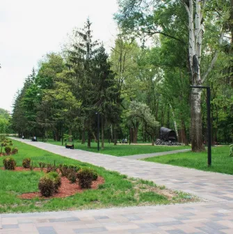 Babyn Yar in Kyiv - wide paved walkway leading through the park towards a symbolic wagon monument amidst the summer greenery