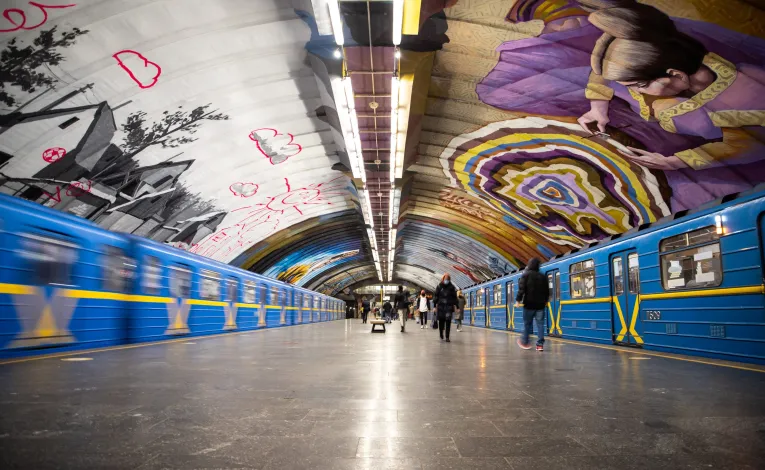 Kyiv Metro station with mural art and trains on the platform in Kyiv