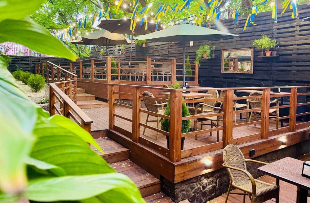 Outdoor restaurant terrace with wooden tables and yellow-blue ribbons