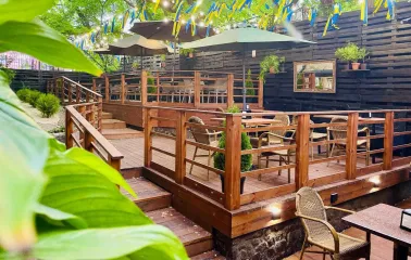 Outdoor restaurant terrace with wooden tables and yellow-blue ribbons