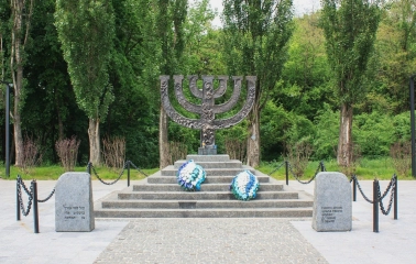Babyn Yar in Kyiv - solemn Menorah monument standing on a stone pedestal surrounded by forest trees honoring the Jewish victims