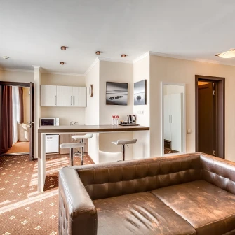 A spacious apartment-style room with a kitchenette and leather sofa at the Bratyslava Hotel in Kyiv