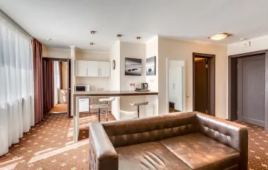 A spacious apartment-style room with a kitchenette and leather sofa at the Bratyslava Hotel in Kyiv