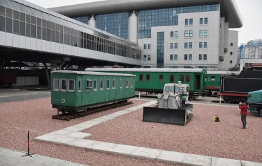 Railway Museum in Kyiv - outdoor exhibition of vintage green railway carriages parked on gravel tracks near the modern glass train station building
