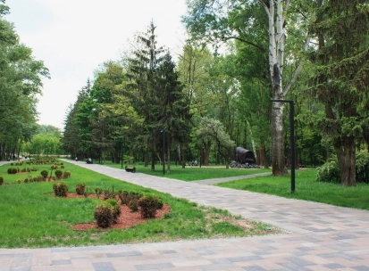Babyn Yar in Kyiv - wide paved walkway leading through the park towards a symbolic wagon monument amidst the summer greenery