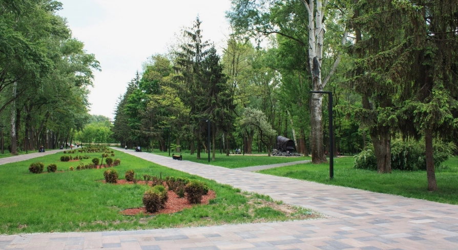 Babyn Yar in Kyiv - wide paved walkway leading through the park towards a symbolic wagon monument amidst the summer greenery
