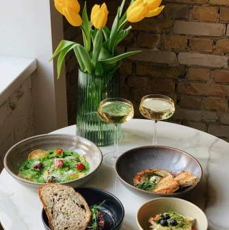 Idealist Coffee - table with pasta toast and wine beside yellow tulips