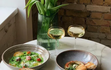 Idealist Coffee - table with pasta toast and wine beside yellow tulips