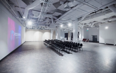 The large Pochayna Event Hall in Kyiv with a screen for projections and seating for the audience
