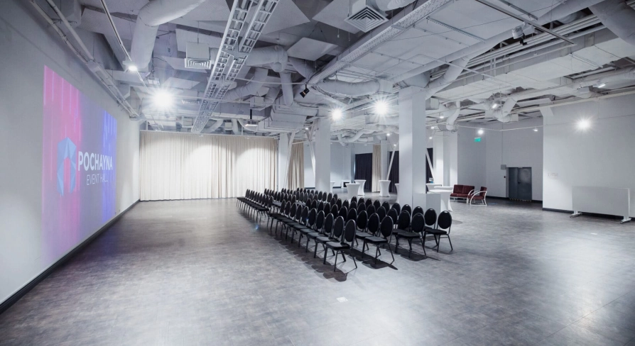 The large Pochayna Event Hall in Kyiv with a screen for projections and seating for the audience