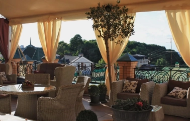 Vozdvyzhenskyi in Kyiv - open-air rooftop terrace with wicker furniture and beige curtains