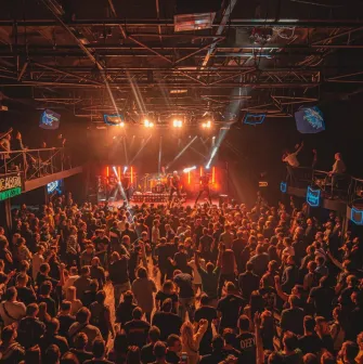 Atlas in Kyiv - high angle view of the packed concert hall with balconies and stage lights beaming through the smoke