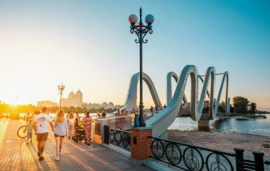 Azov Wave Bridge in Kyiv - pedestrians walking on a wavy bridge bathed in the golden light of the sunset