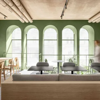 Wide perspective shot showing the modern furniture and architectural green arches of the interior
