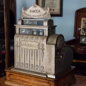 Pharmacy Museum in Kyiv - ornate antique silver "National" cash register standing on a wooden counter next to a retro telephone