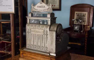 Pharmacy Museum in Kyiv - ornate antique silver "National" cash register standing on a wooden counter next to a retro telephone