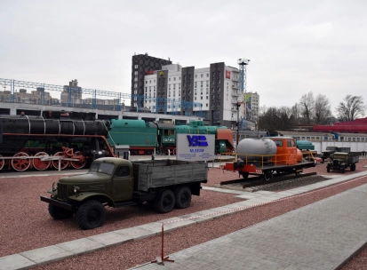 Railway Museum in Kyiv - open-air museum grounds displaying a variety of black steam engines, green locomotives, and vintage trucks on red gravel