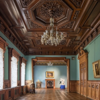 Kyivska Kartynna Halereia in Kyiv - a long hall with a dark wooden ceiling, a crystal chandelier and green walls