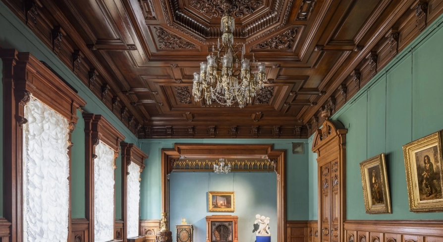 Kyivska Kartynna Halereia in Kyiv - a long hall with a dark wooden ceiling, a crystal chandelier and green walls