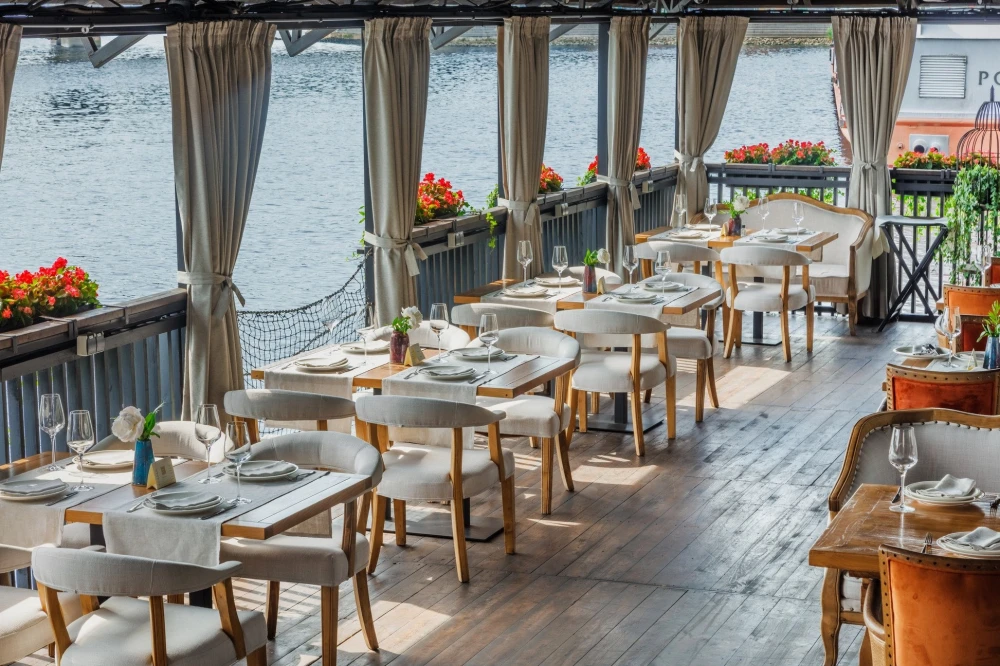 Restaurant Khutorets na Dnipri - waterfront terrace with white dining chairs and river view