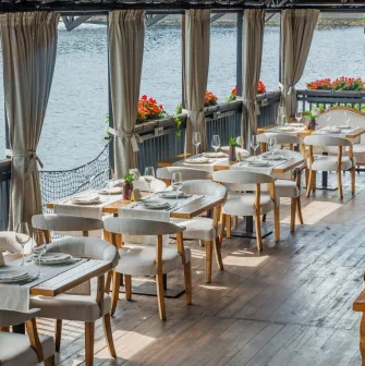 Restaurant Khutorets na Dnipri - waterfront terrace with white dining chairs and river view