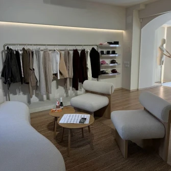 Concept 1 Boutique in Kyiv - cozy lounge area with modern white bouclé armchairs surrounded by fashion collections