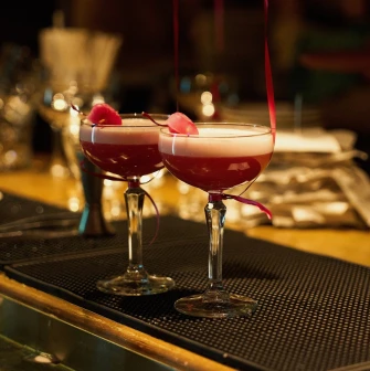Tisto Syr i Titka Bella – two pink cocktails with foam and petals on bar counter