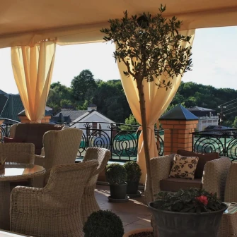 Vozdvyzhenskyi in Kyiv - open-air rooftop terrace with wicker furniture and beige curtains