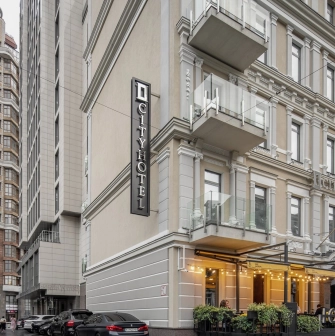 City Hotel in Kyiv - beige hotel building facade with vertical sign and street terrace
