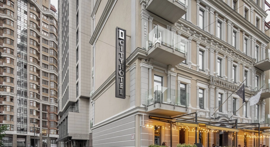 City Hotel in Kyiv - beige hotel building facade with vertical sign and street terrace