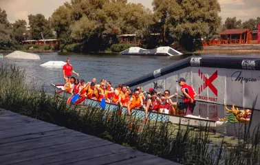 X-Park in Kyiv - team in orange life vests rowing a dragon boat on the river