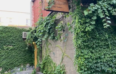 Chaguan in Kyiv - brick facade covered in green ivy with wooden sign and bench