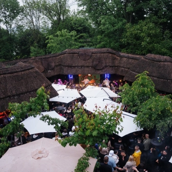 Kureni - crowded outdoor terrace with umbrellas and thatched roofs