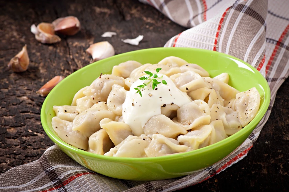 A plate of dumplings with sour cream