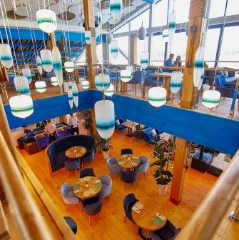 Restaurant Prychal - multi-level dining hall with wooden floors and unique hanging blue lamps