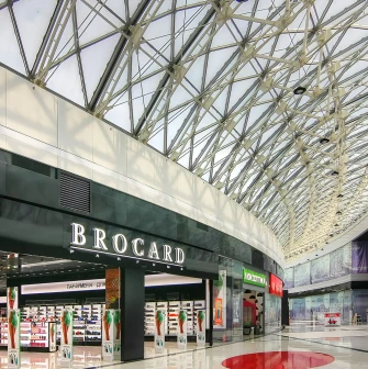 Bright interior corridor of Lavina Mall with glass roof and Brocard store