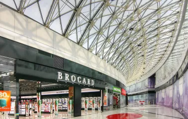 Bright interior corridor of Lavina Mall with glass roof and Brocard store