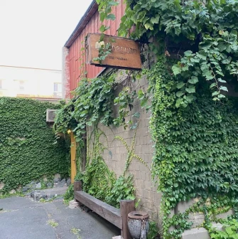 Chaguan in Kyiv - brick facade covered in green ivy with wooden sign and bench