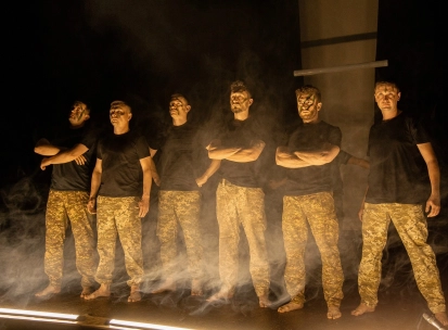Teatr Voiennykh Dii in Kyiv - powerful lineup of actors in military trousers standing in stage smoke under dramatic side lighting
