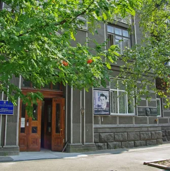 Muzei Tychyny in Kyiv - exterior entrance to the museum apartment located in a historic grey building with a large portrait of the poet displayed outside