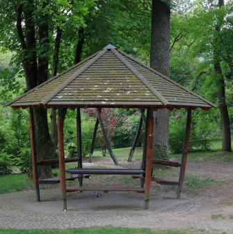 Park Partyzanskoi Slavy in Kyiv - rustic hexagonal wooden gazebo with a tiled roof standing in a secluded shady spot among green trees