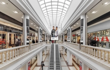 Gallery of shops in the Globus shopping center with an escalator and a light roof