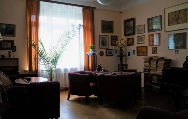 Muzei Tychyny in Kyiv - atmospheric living room featuring a grand piano, velvet armchairs, and a wall gallery of framed paintings