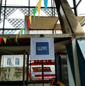 The entrance to the Podilsky Shuk market with flags and a white banner in an industrial building in Podil