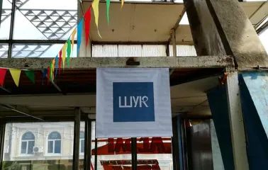 The entrance to the Podilsky Shuk market with flags and a white banner in an industrial building in Podil