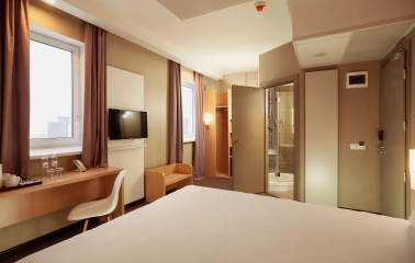 Ibis Railway Station in Kyiv - bedroom interior with white bed and open door