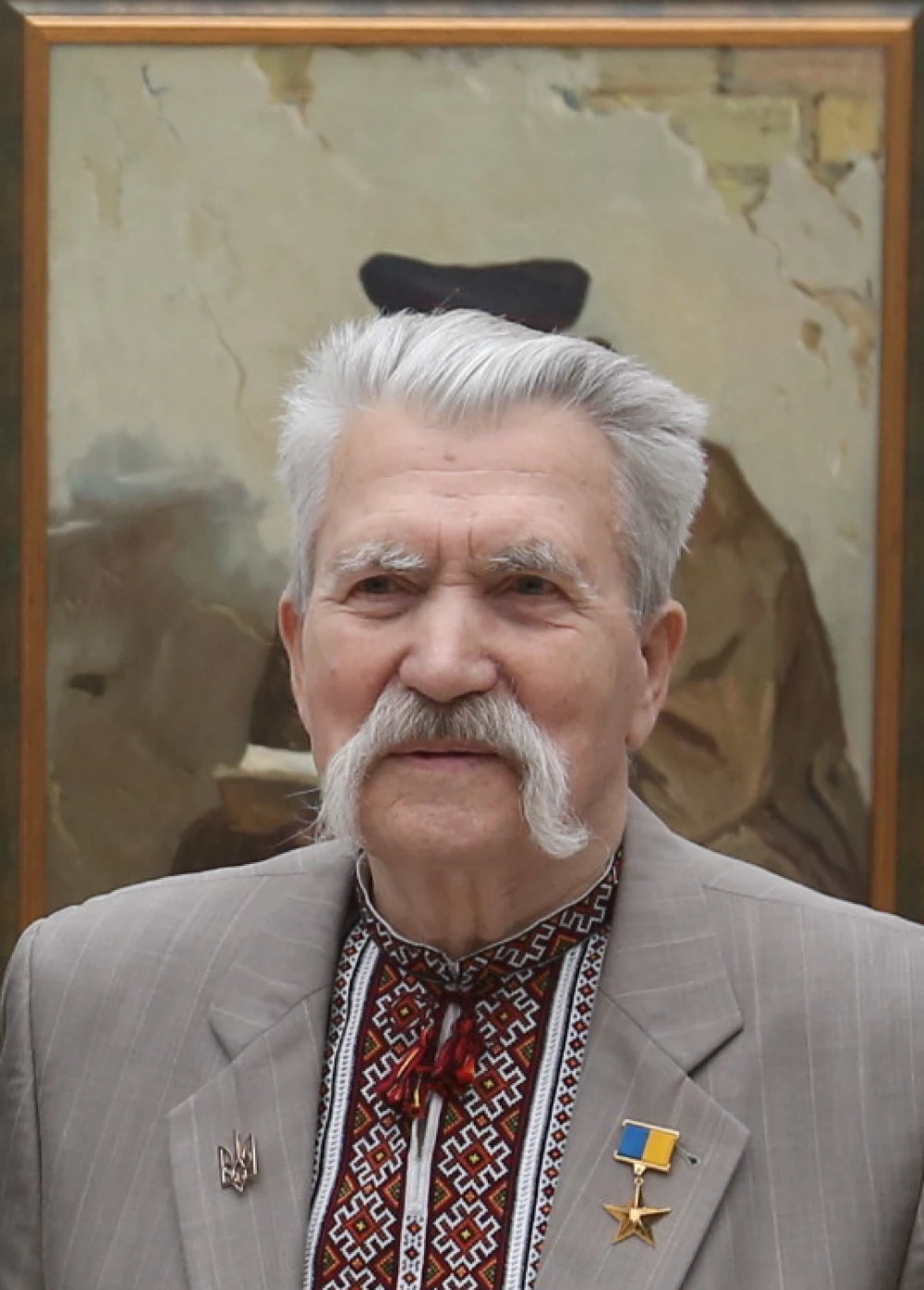 Levko Lukianenko in an embroidered shirt and suit jacket against the background of a painting