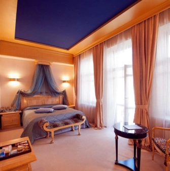 Elegant room at the Opera Hotel in Kyiv with a four-poster bed and blue ceiling
