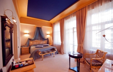 Elegant room at the Opera Hotel in Kyiv with a four-poster bed and blue ceiling