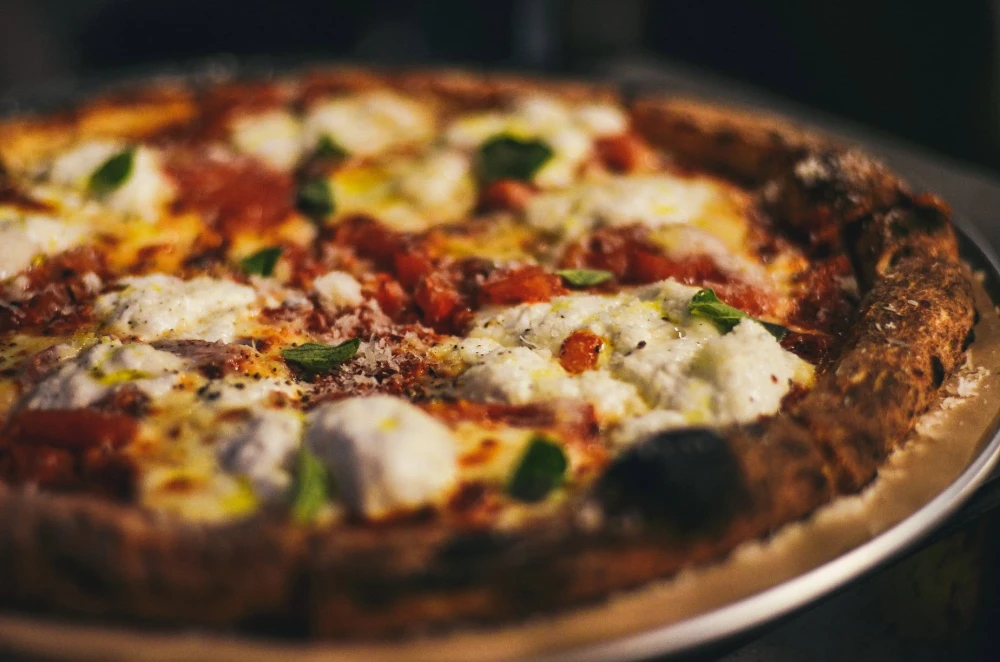 Appetizing pizza with cheese and greens from a close distance at Italiiska redaktsiia